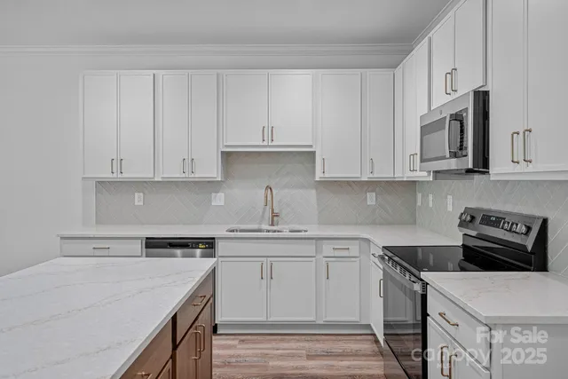 a kitchen with stainless steel appliances granite countertop a sink stove and white cabinets