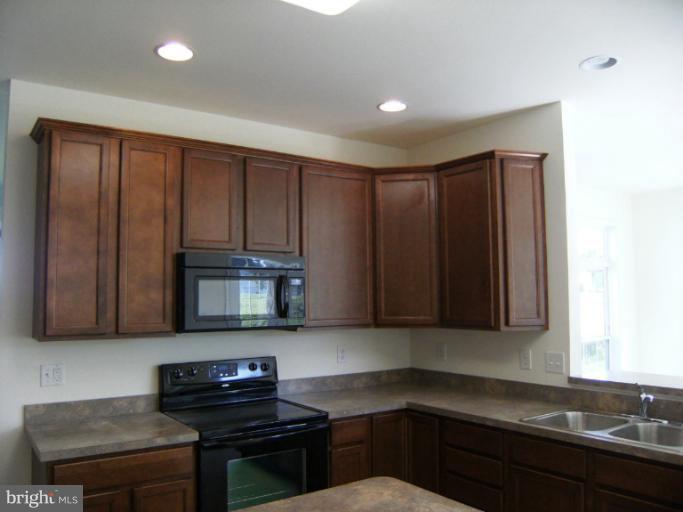 783 Rivanna Run Falling Waters, WV 25419 - Photo 11 of 30 a kitchen with granite countertop wooden cabinets and black appliances
