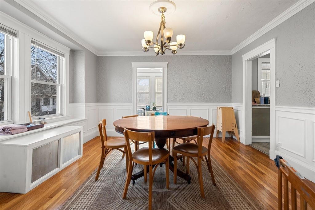 26-28 Alton Street Arlington, MA 02474 - Photo 26 of 41 a dining room with wooden floor a chandelier a wooden table and chairs