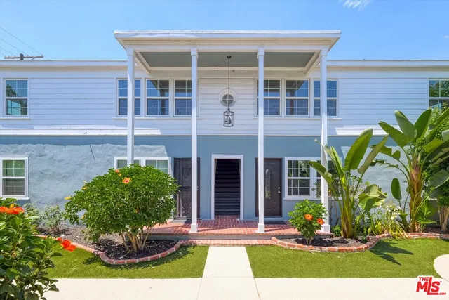 a front view of a house with a yard and potted plants