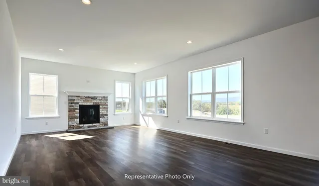 an empty room with windows a fireplace and wooden floor
