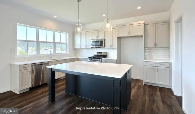 a kitchen with kitchen island a sink appliances and cabinets