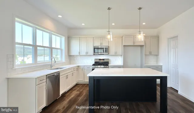 a kitchen with a sink a stove a refrigerator and white cabinets