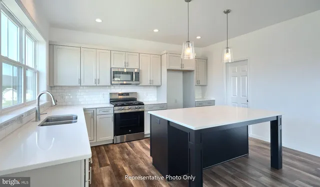 a kitchen with kitchen island a sink appliances and cabinets