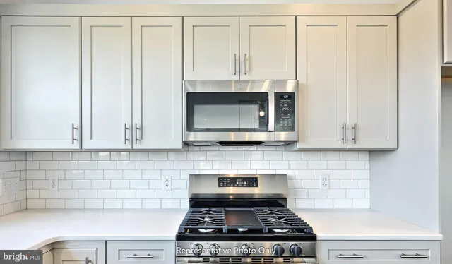 a kitchen with granite countertop a stove a sink and white cabinets