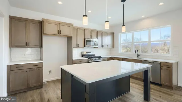 a kitchen with kitchen island a sink dishwasher a stove a refrigerator and island with wooden floor