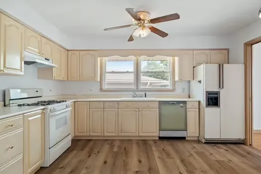 a kitchen with white cabinets white appliances and window