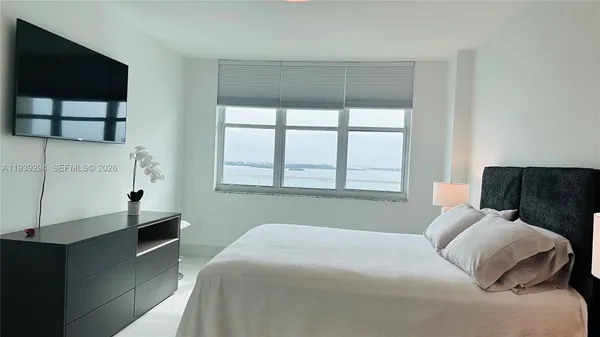 a bedroom with a bed and a flat tv screen on the dresser