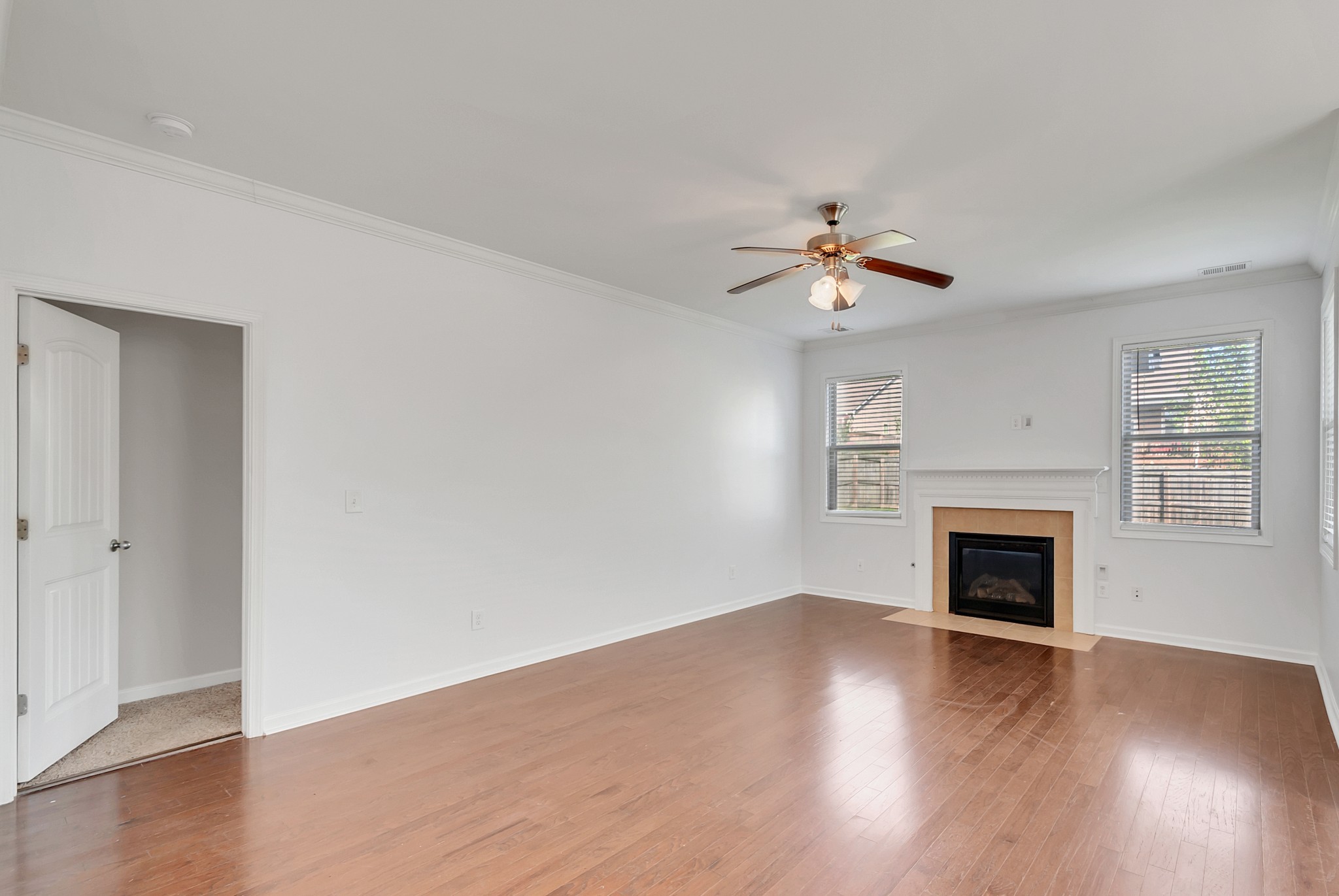 3005 Alan Drive Spring Hill, TN 37174 - Photo 18 of 41 an empty room with wooden floor fireplace chandelier fan and windows