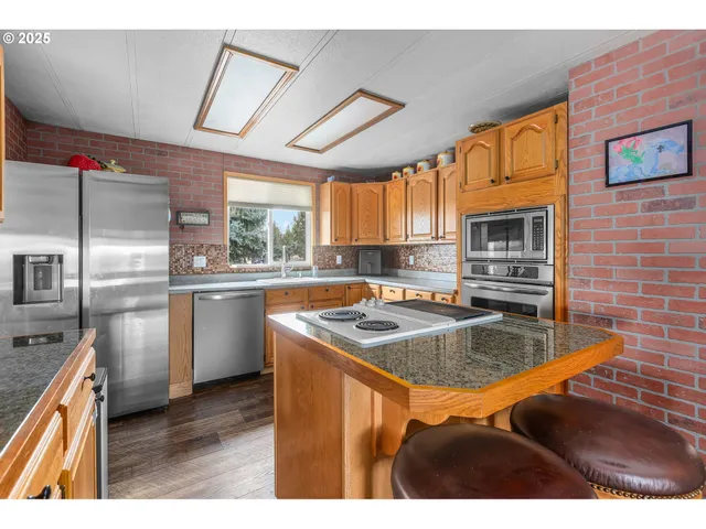 a kitchen with stainless steel appliances granite countertop a sink a stove and a refrigerator