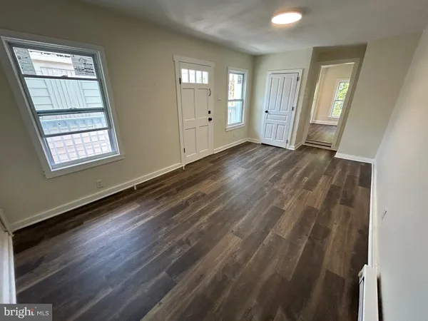 a view of an empty room with wooden floor and window
