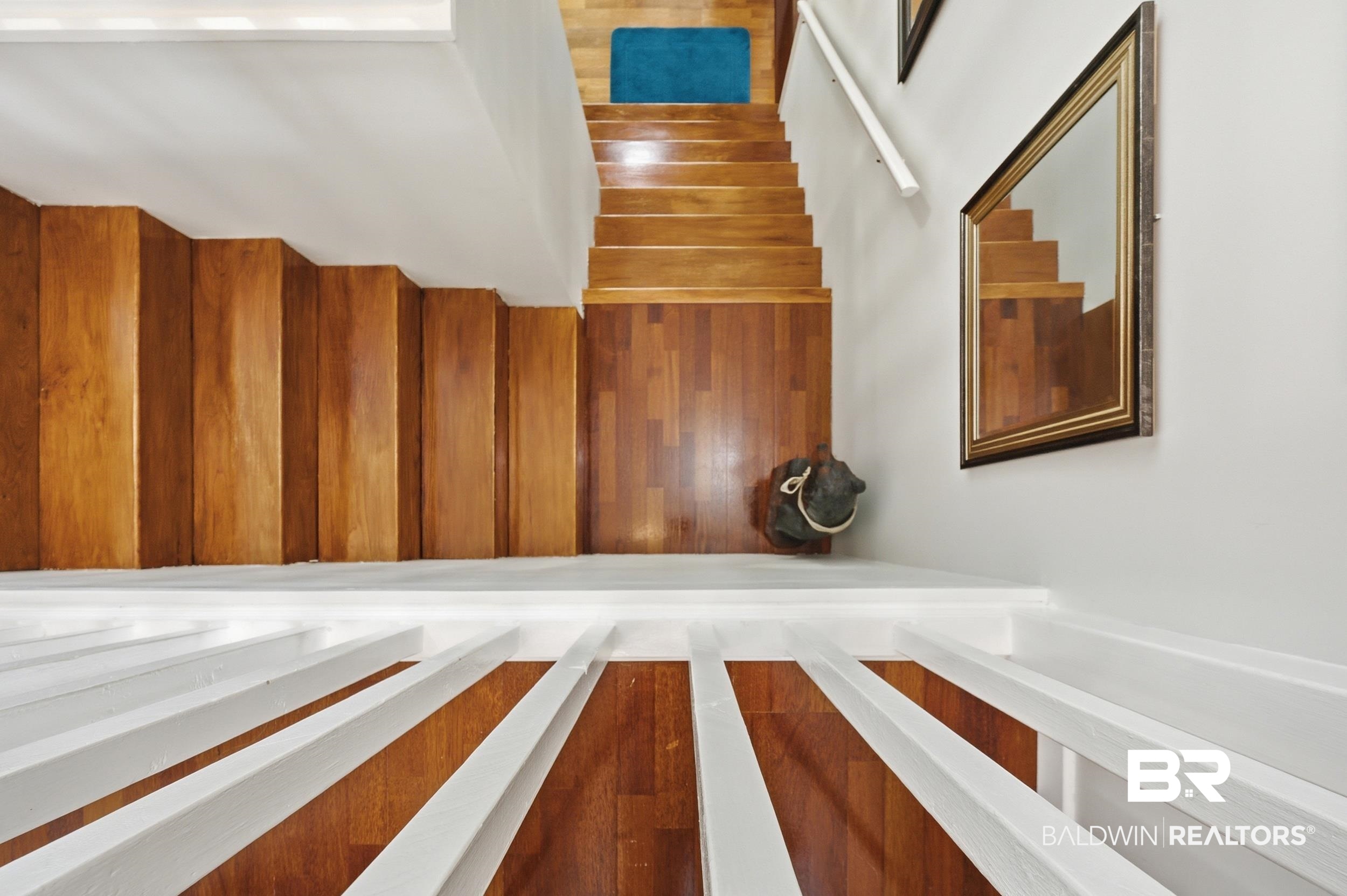 15855 Calvin Richerson Road Bay Minette, AL 36507 - Photo 43 of 83 Hardwood staircase with white risers and railings, complemented by a decorative wall mirror