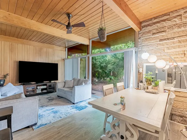 a living room with furniture a flat screen tv and a floor to ceiling window