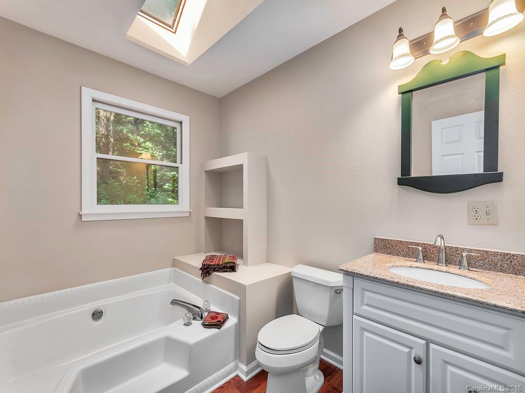 322 Old Country Road Waynesville, NC 28786 - Photo 10 of 12 a bathroom with a granite countertop toilet a sink a mirror and a window