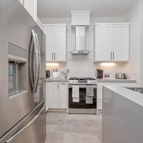 a large white kitchen with kitchen island a counter top space a sink and appliances