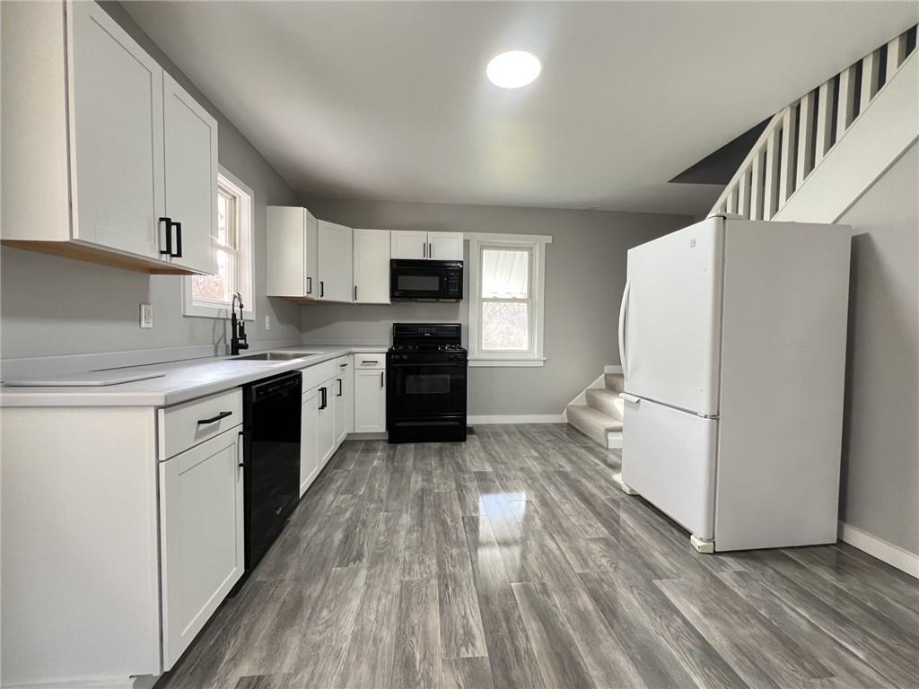 37 Lebanon Avenue Uniontown, PA 15401 - Photo 6 of 15 a kitchen with granite countertop a refrigerator a sink dishwasher and a stove with wooden floor