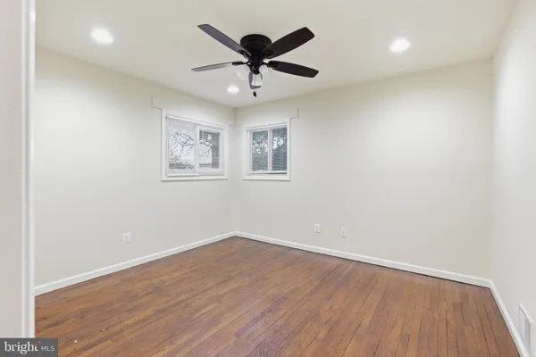 an empty room with wooden floor and ceiling fan