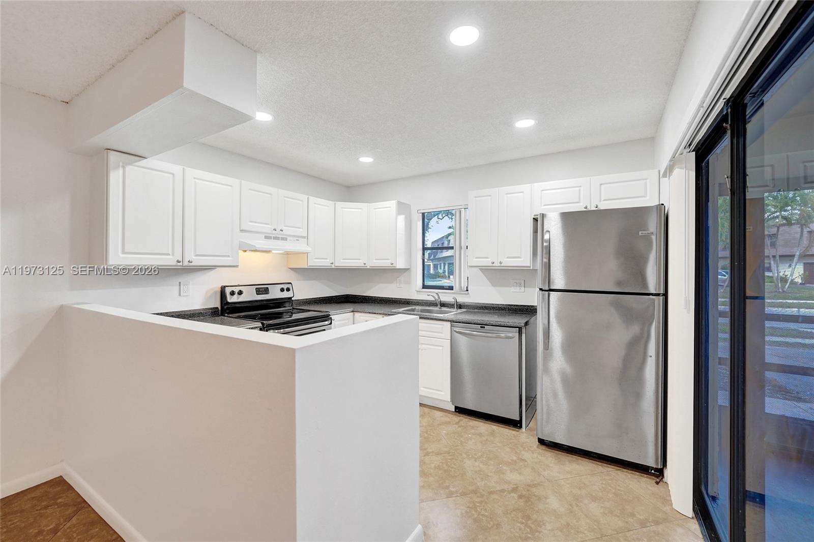 9340 Southwest 61st Way, Unit B Boca Raton, FL 33428 - Photo 3 of 25 a kitchen with stainless steel appliances granite countertop a refrigerator a sink a stove a microwave and white cabinets