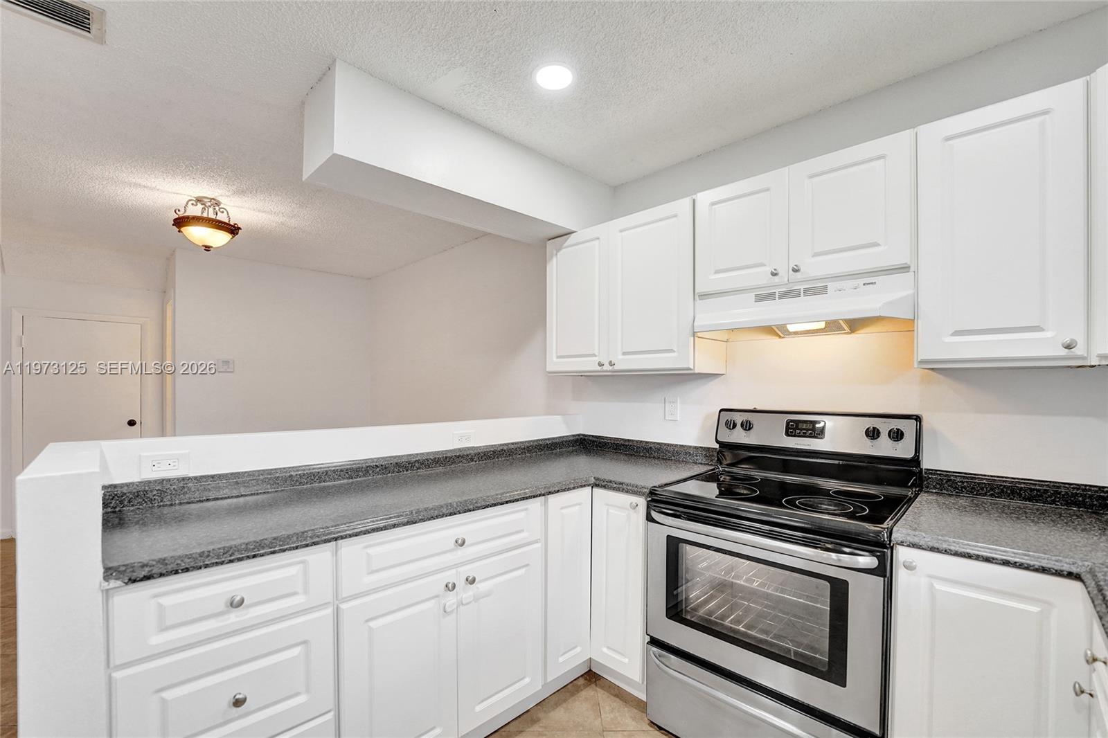 9340 Southwest 61st Way, Unit B Boca Raton, FL 33428 - Photo 5 of 25 a kitchen with granite countertop white cabinets and stainless steel appliances