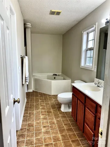 a large kitchen with stainless steel appliances granite countertop a sink dishwasher a stove and white cabinets with wooden floor