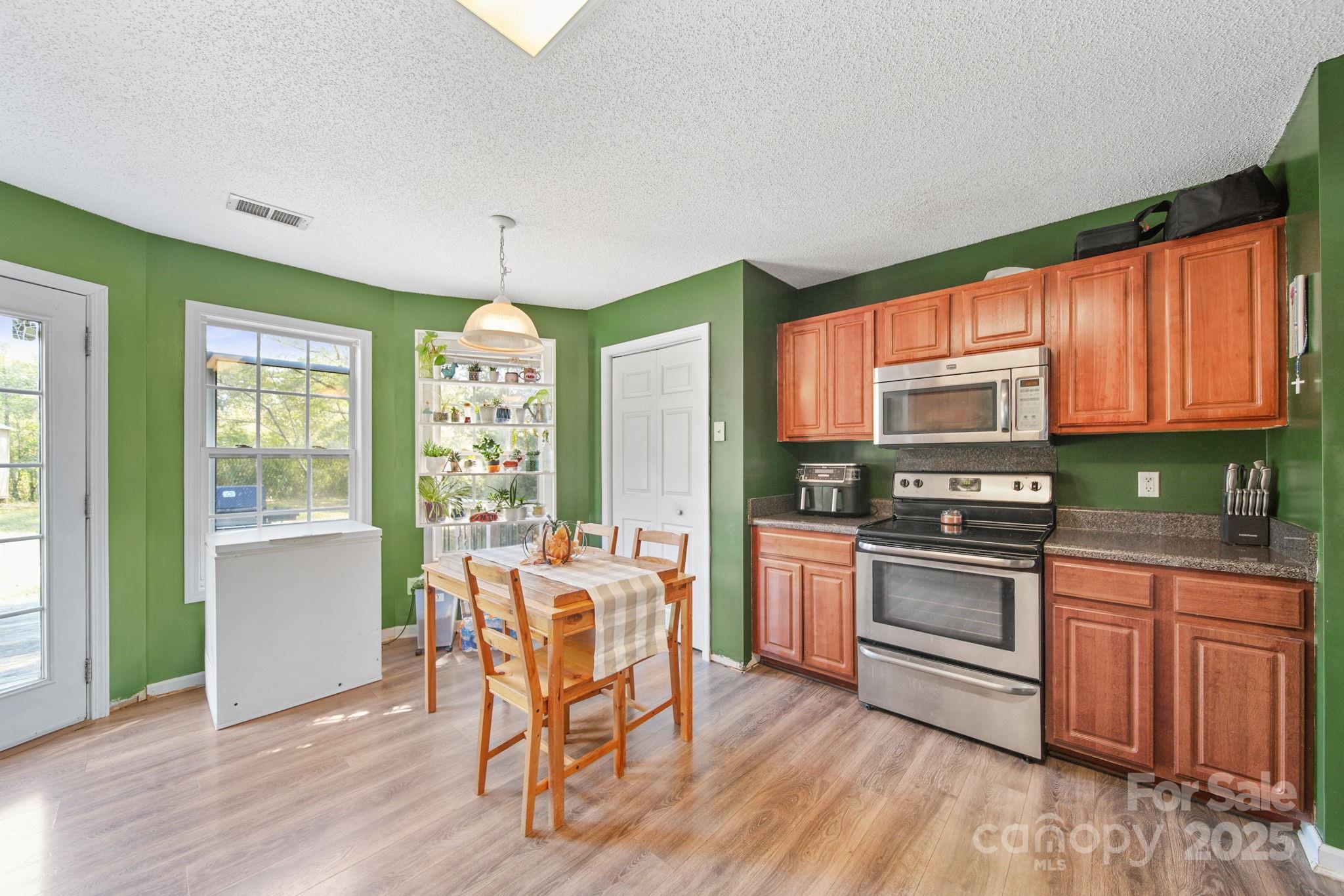 1723 Faulks Church Road Marshville, NC 28103 - Photo 20 of 27 a kitchen with stainless steel appliances granite countertop a stove top oven a sink dishwasher and white cabinets with wooden floor