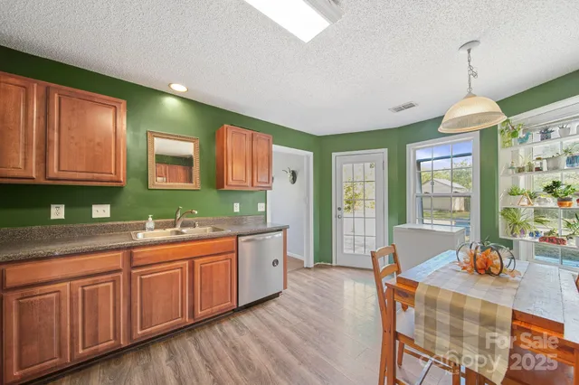 a kitchen with stainless steel appliances granite countertop a refrigerator a sink dishwasher a stove and a dining table with wooden floor