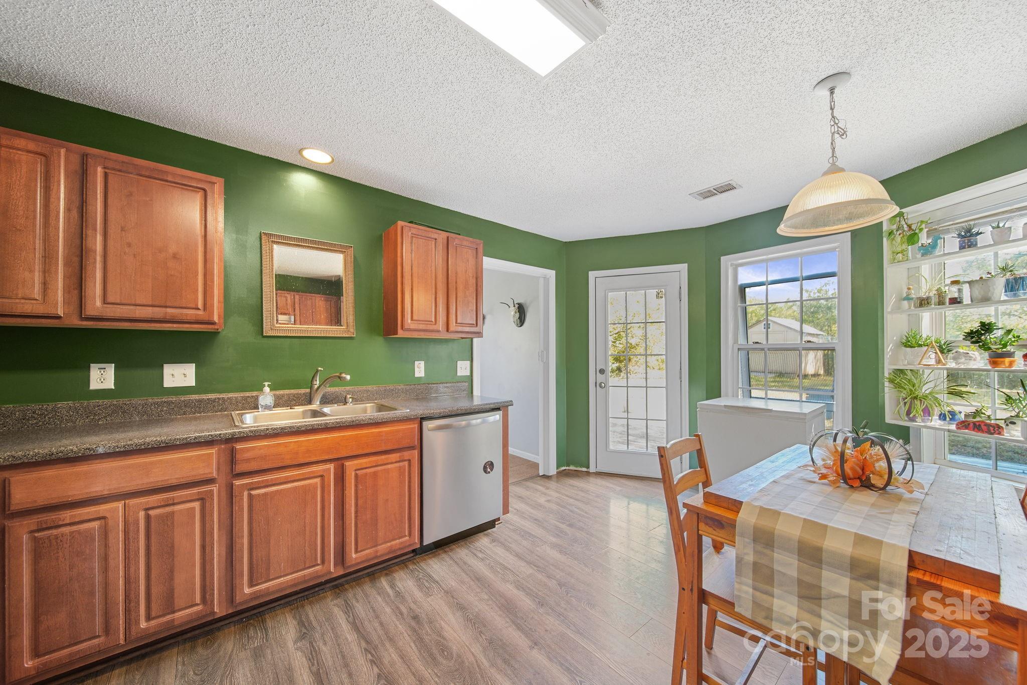 1723 Faulks Church Road Marshville, NC 28103 - Photo 21 of 27 a large kitchen with stainless steel appliances granite countertop a sink dishwasher a stove and white cabinets with wooden floor