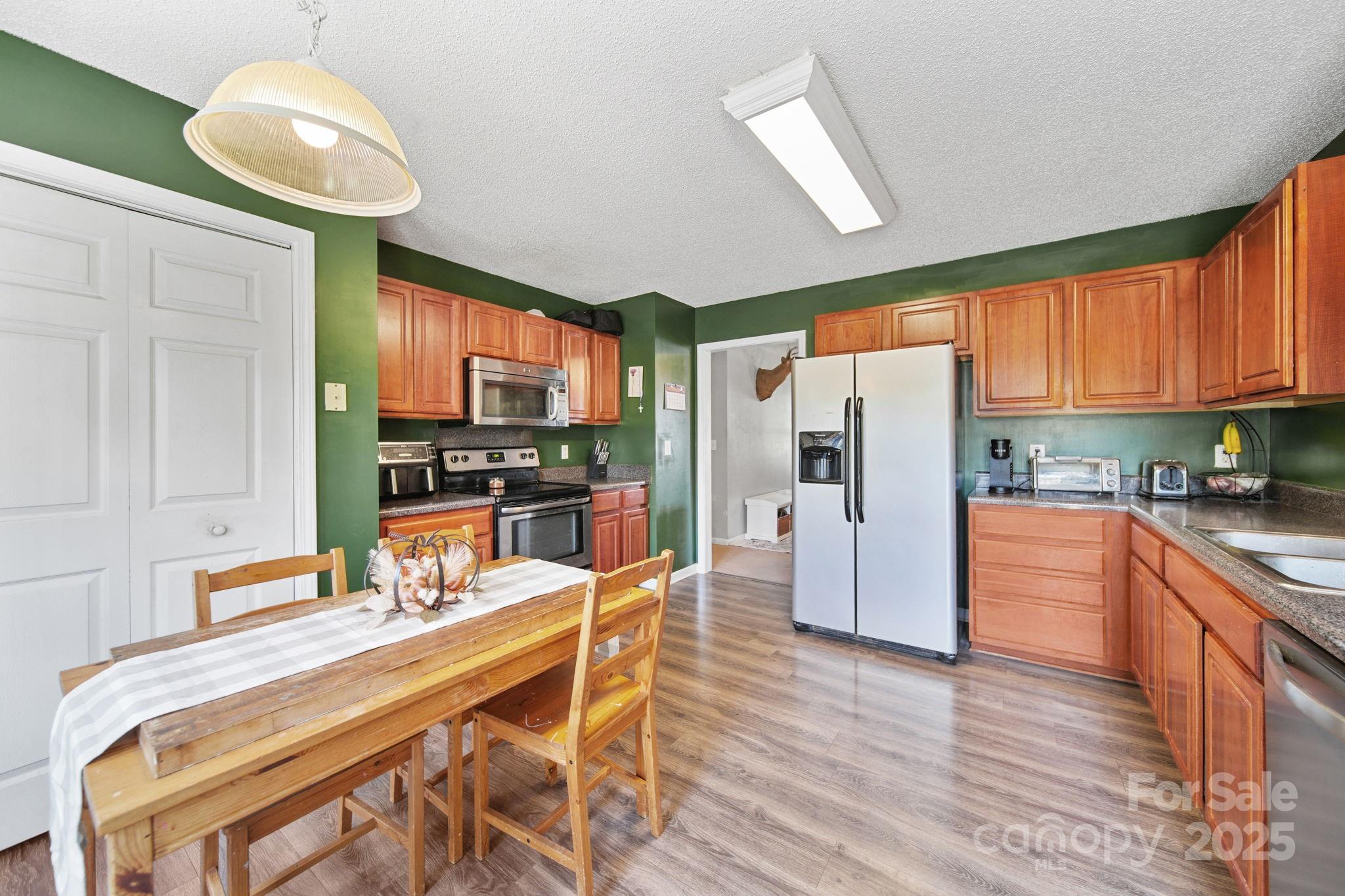 1723 Faulks Church Road Marshville, NC 28103 - Photo 24 of 27 a kitchen with stainless steel appliances granite countertop a refrigerator a sink dishwasher a stove and a dining table with wooden floor