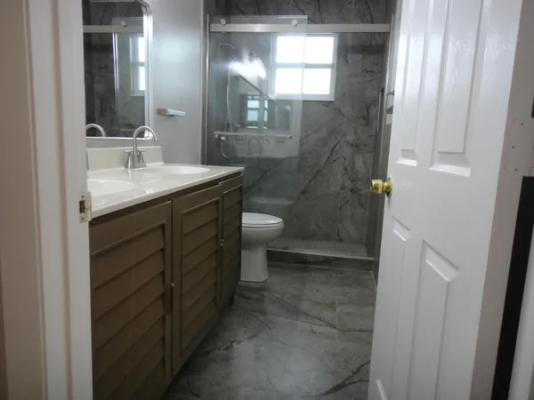 a bathroom with a granite countertop sink toilet and shower