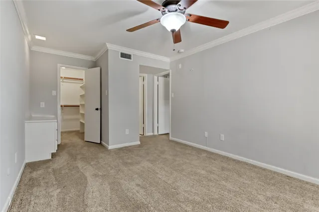 an empty room with closet and a ceiling fan