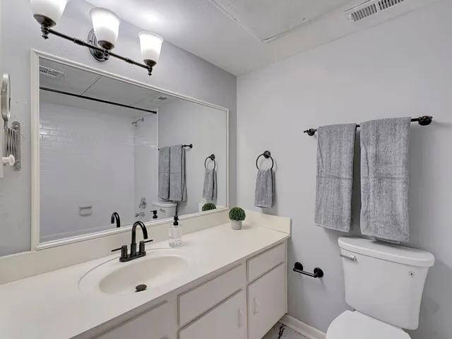 a bathroom with double vanity sink a toilet and a mirror