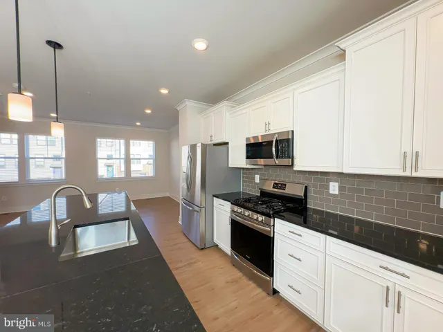 a kitchen with stainless steel appliances granite countertop a sink a stove and a refrigerator