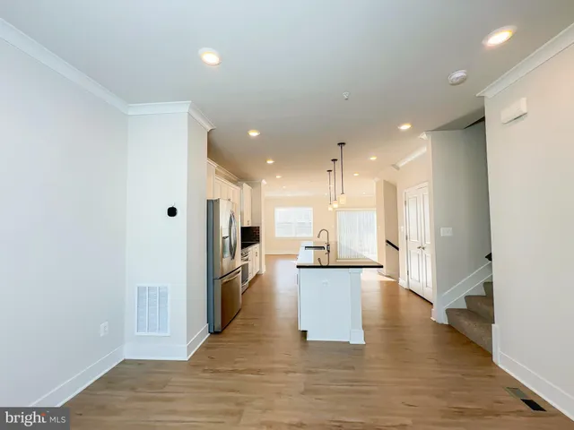 a view of a kitchen with refrigerator and wooden floor