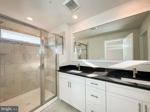 a bathroom with a double vanity sink a mirror and a shower