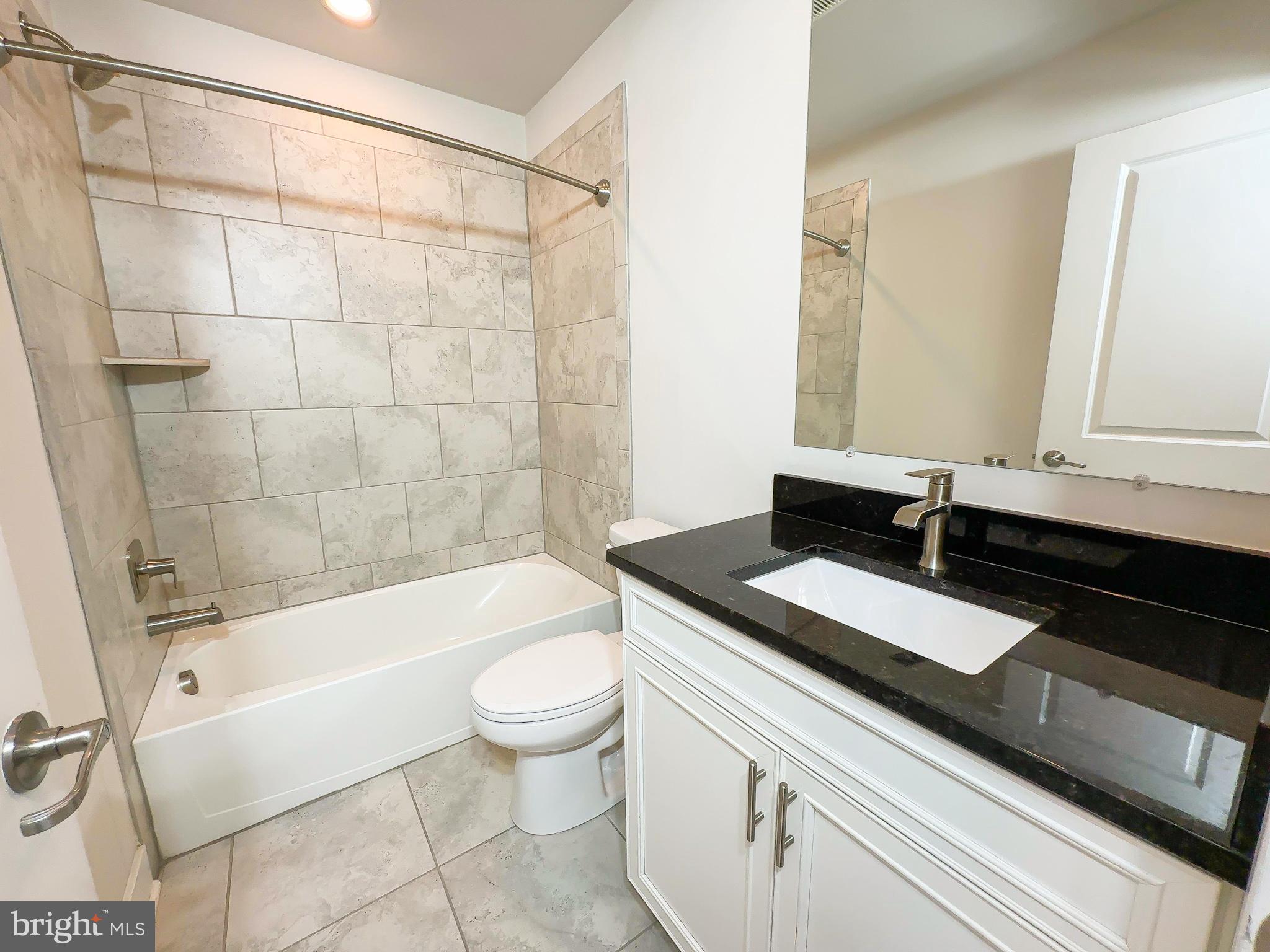 822 Teacher MItchell Road Glen Burnie, MD 21060 - Photo 35 of 53 a bathroom with a granite countertop sink a toilet a mirror and bathtub