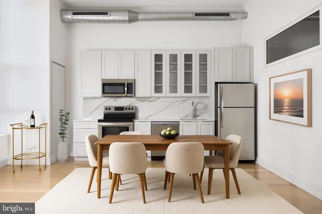 a kitchen with stainless steel appliances granite countertop a dining table chairs refrigerator a sink and dishwasher