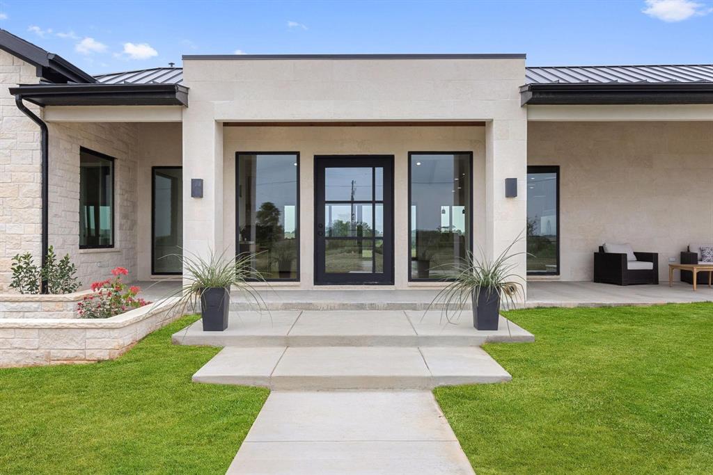 Entrance to property with a standing seam roof, ametal roof, a lawn, and a patio area