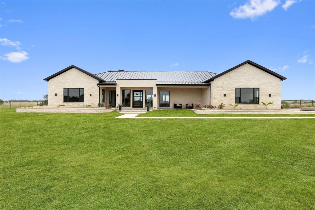 6505 County Road 1126B Godley, TX 76044 - Photo 2 of 39 Back of house with stone siding, a standing seamroof, a metal roof, and covered porch