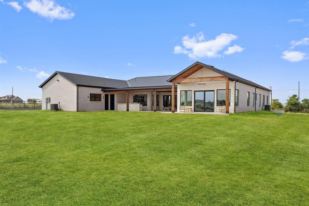 6505 County Road 1126B Godley, TX 76044 - Photo 37 of 39 Rear view of property with a patio, a lawn, astanding seam roof, and a metal roof