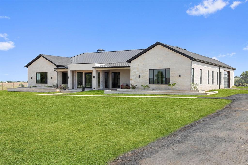 6505 County Road 1126B Godley, TX 76044 - Photo 38 of 39 Rear view of property featuring a lawn, coveredporch, a metal roof, stone siding, and brick siding