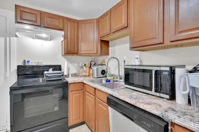 a kitchen with granite countertop a sink stainless steel appliances and cabinets