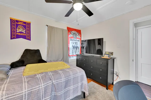 a bedroom with a bed and a flat tv screen on dresser
