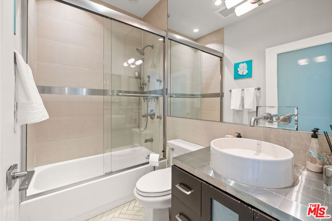 11822 Goshen Avenue, Unit 301 Los Angeles, CA 90049 - Photo 20 of 29 a bathroom with a granite countertop sink a toilet a mirror and shower