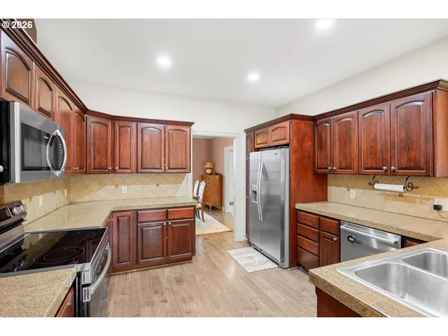 a kitchen with stainless steel appliances granite countertop a refrigerator a stove and a sink with wooden cabinets