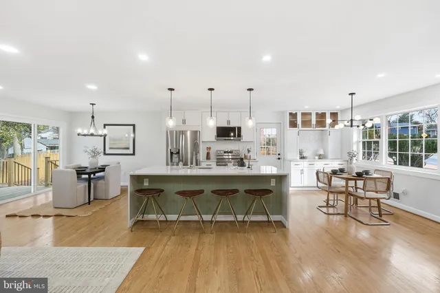 a kitchen with stainless steel appliances a stove a sink a microwave a dining table and chairs
