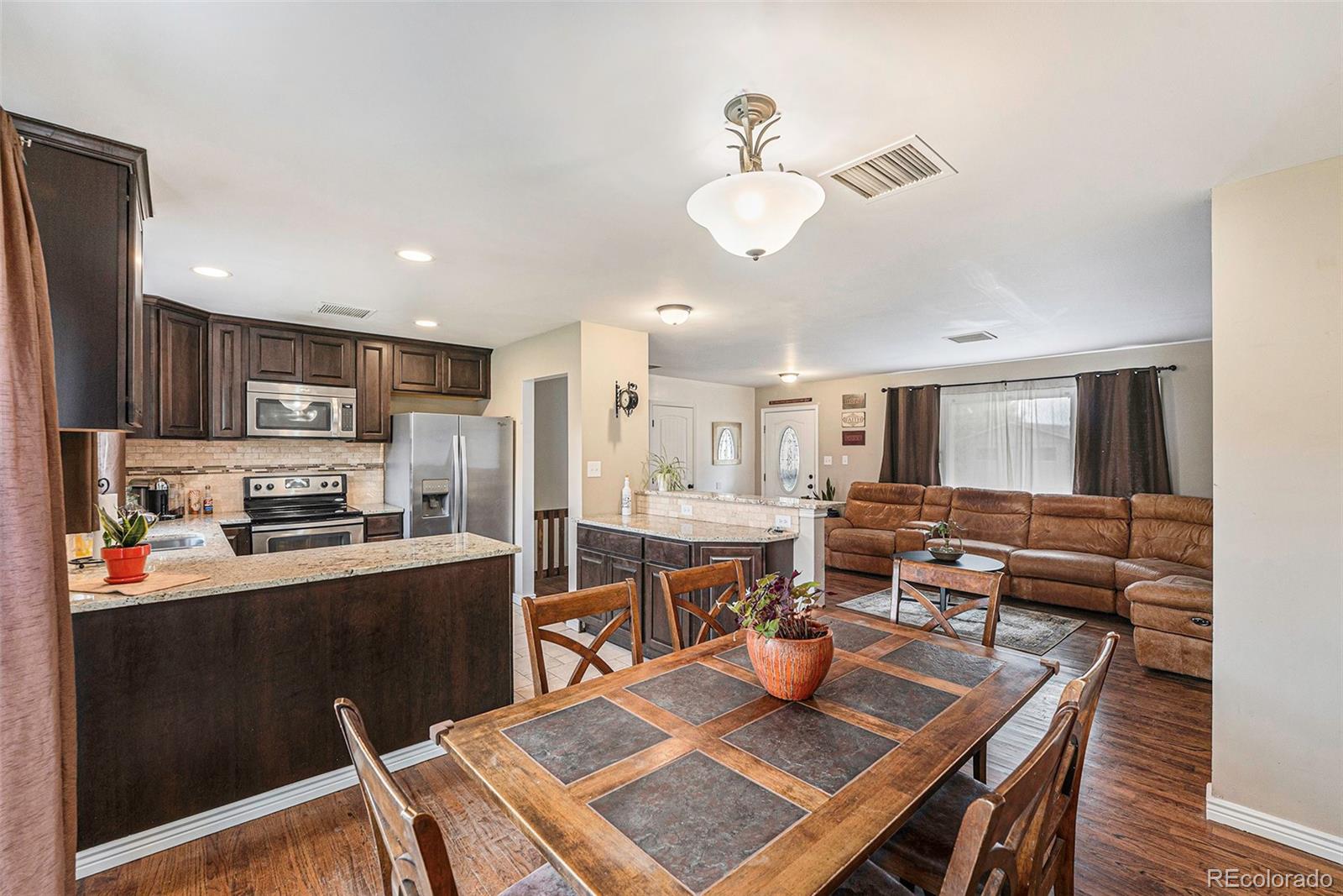 2872 South Gray Way Denver, CO 80227 - Photo 9 of 35 a kitchen with stainless steel appliances granite countertop a stove a refrigerator a kitchen island a dining table and chairs with wooden floor