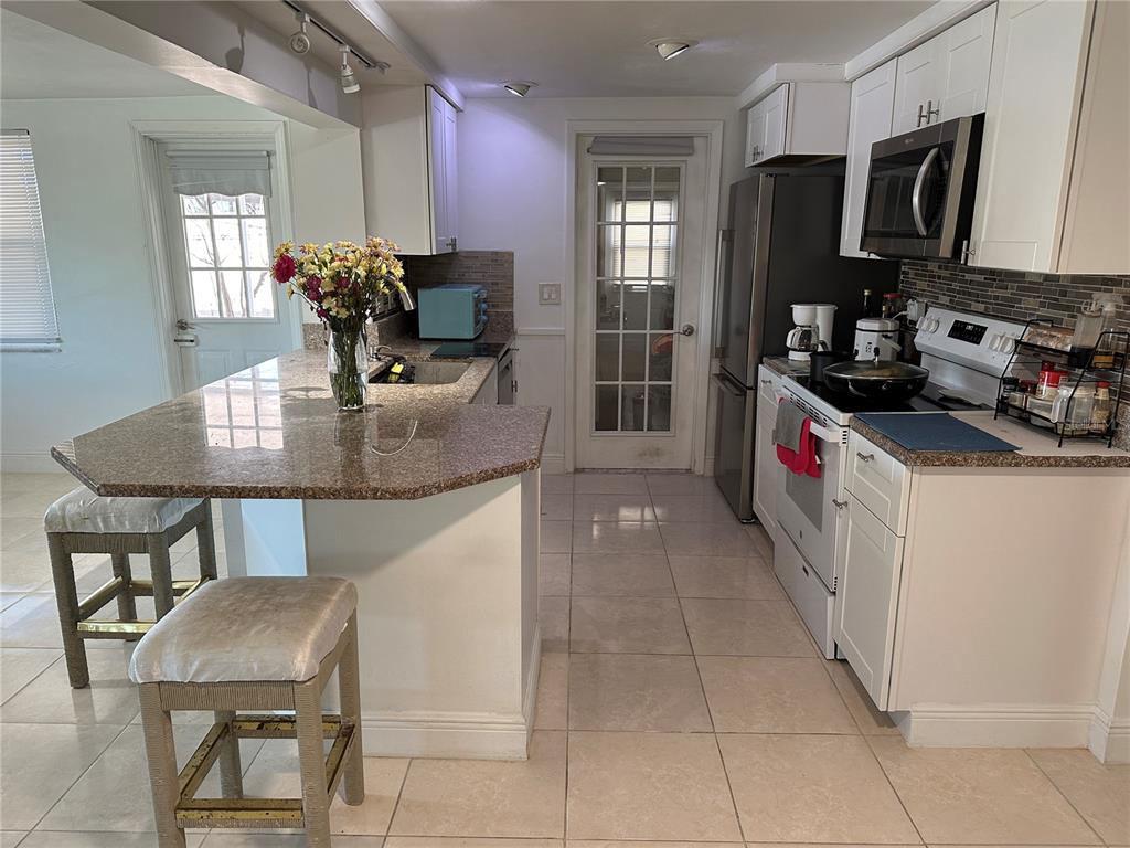 12613 4th Isle Hudson, FL 34667 - Photo 7 of 42 a kitchen with stainless steel appliances a dining table chairs microwave and sink