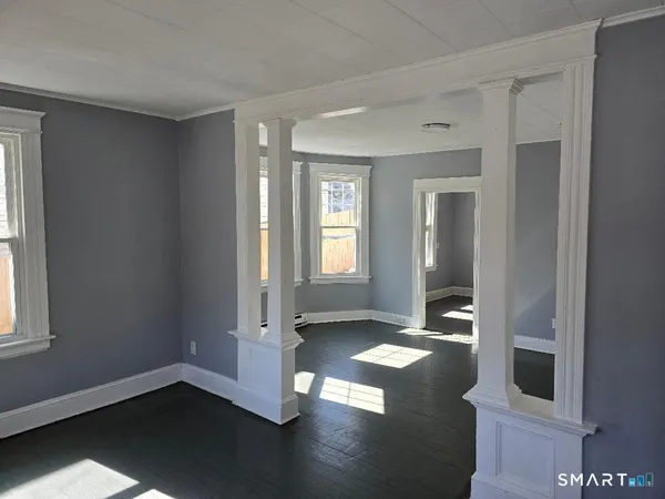 an empty room with wooden floor and windows