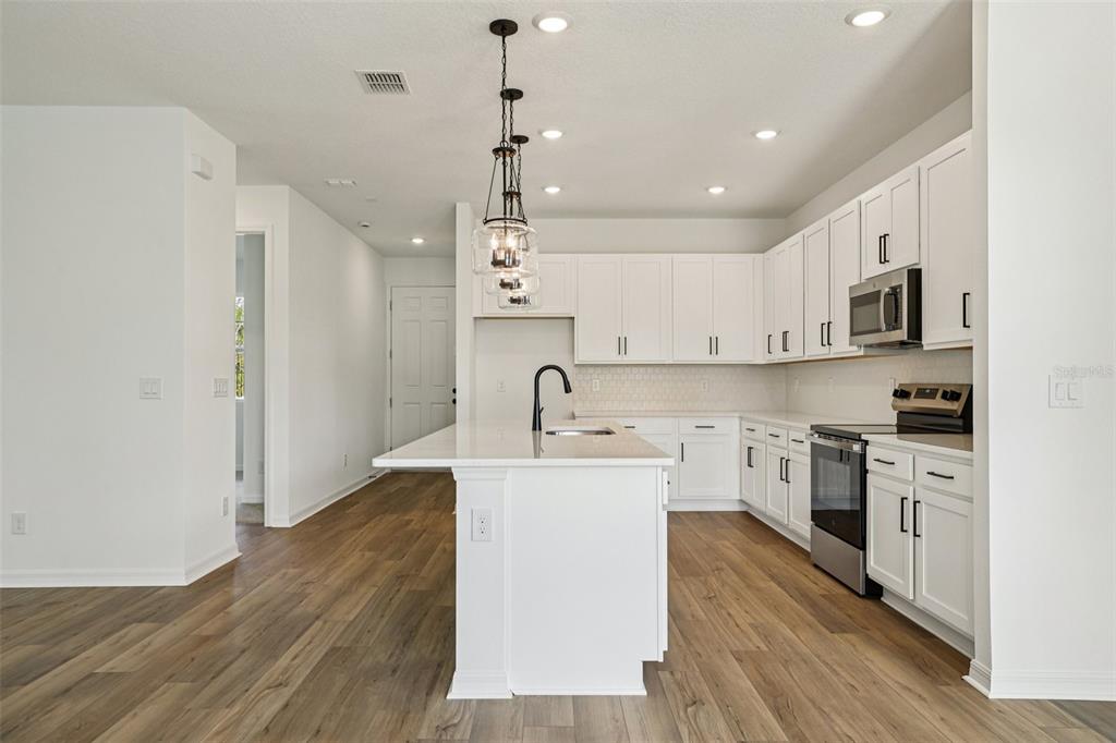 2491 Zuni Road St. Cloud, FL 34771 - Photo 12 of 42 a large kitchen with stainless steel appliances granite countertop a sink a stove a refrigerator and cabinets