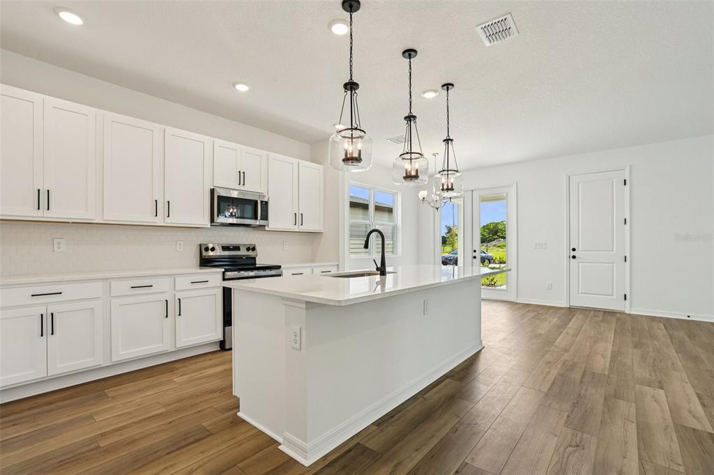 2491 Zuni Road St. Cloud, FL 34771 - Photo 15 of 42 a large kitchen with kitchen island a stove a sink a center island and wooden floor